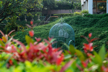 Big bird cage decoration with blurred leaf bush. background for park and garden concept