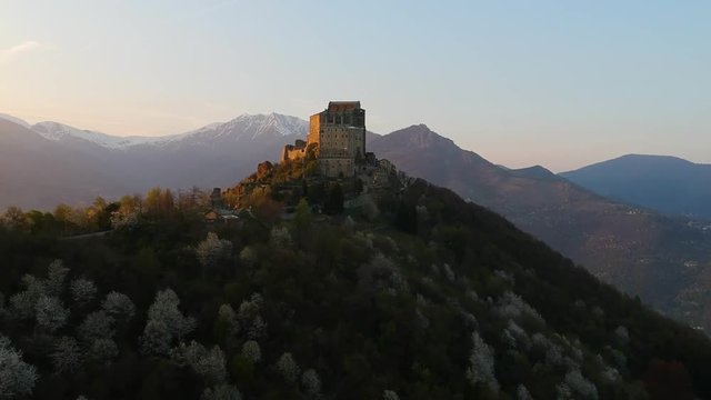 The Sacra di San Michele (Saint Michael's) Abbey, Turin, Italy, sunset shot aerial with mountains of Susa valley in background. Aerial view