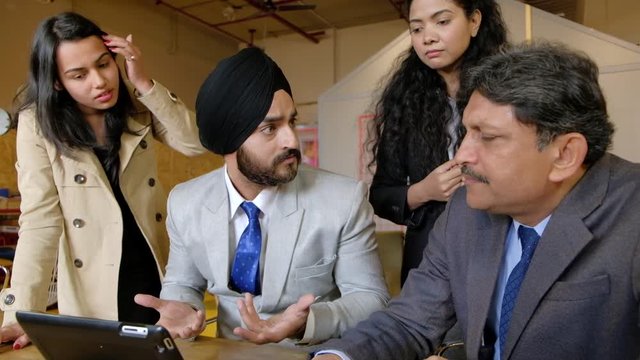 Indian boss with turban is really angry with his junior and senior team as he looks at their failure and is completely disappointed with everyone as he puts his head down in complete incompetence