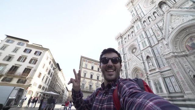 Happy tourist man takes photo on travel in Florence. Smiling man happy taking self portrait outdoor by Cathedral during vacation holidays in Florence, Tuscany, Italy, Europe