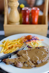 Grilled pork with black pepper sauce, vegetables and french fries