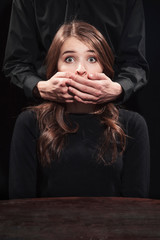 Man covered his mouth with a young woman on a black background - obrazy, fototapety, plakaty