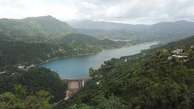 AERIAL: still shot look down at a dam and precious lake between the mountain tops of Utuado, Puerto Rico.