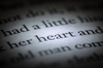 The word heart in a book close-up macro. Vintage, grunge, old, retro style photo.