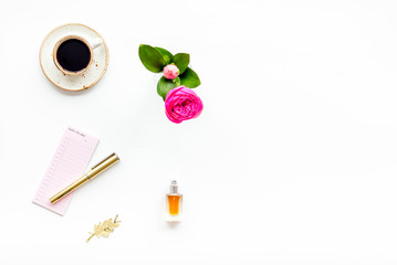 Home work desk, feminine workplace. Notebook and stationery near pink flowers and coffee on white background top view copy space