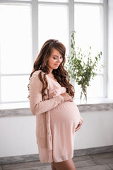 Beautiful smiling pregnant woman is holding belly