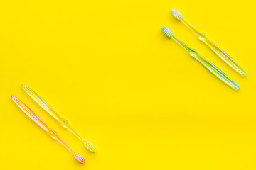 Clean teeth. Plastic toothbrushes on yellow background top view copy space