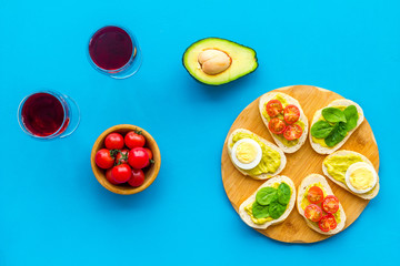 Healthy snacks. Set of toasts with vegetables like avocado, guacamole, rocket, cherry tomatoes on blue background top view