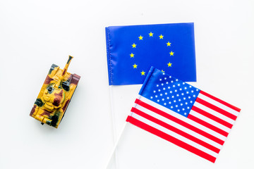 War, confrontation concept. European Union, USA. Tanks toy near european and american flag on white background top view