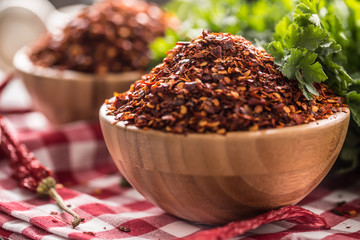Dried and crushed chili peppers in wooden bowles with parsley herbs
