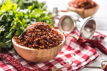 Dried and crushed chili peppers in wooden bowles with parsley herbs