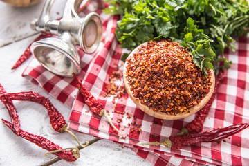 Dried and crushed chili peppers in wooden bowles with parsley herbs