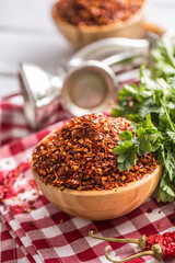 Dried and crushed chili peppers in wooden bowles with parsley herbs