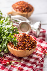 Dried and crushed chili peppers in wooden bowles with parsley herbs