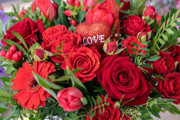 a festive bouquet of a variety of red flowers and a heart with the inscription love for Valentine's day and other holidays