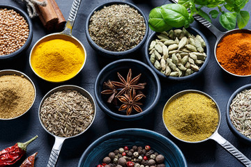 Colorful, aromatic spices in bowls on a dark background.