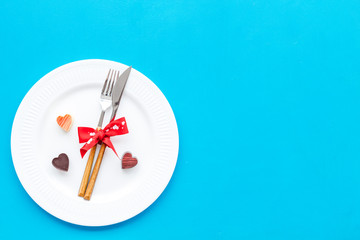 Dating on Valentine's day concept. Festive dishes, tableware on plate on blue background top view space for text