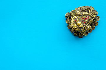Buddhist symbol. Oriental three legged toad with gold coins on blue background top view copy space
