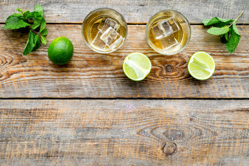 Fototapeta na wymiar Alcoholic beverage. Whiskey with ice, mint and lime on dark wooden background top view copy space