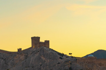 Obraz premium Genoese fortress in Sudak and the temple with an arcade on the background of the evening sky, Crimea. Beautiful evening landscape.