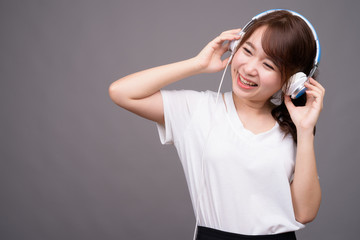 Young beautiful Asian woman wearing headphones for music