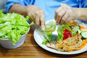 Asian senior or elderly old lady woman patient eating breakfast healthy food with hope and happy while sitting and hungry on bed in hospital.