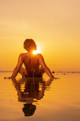 Fototapeta premium Silhouette of a young and fit woman on the beach at sunset
