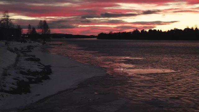 Time lapse of river in sunset, with blocks of ice floating down the stream.