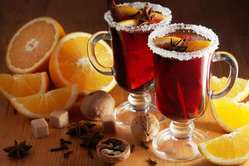 Two cups with ready mulled wine with anise, cinnamon and nuts around	