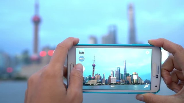 Phone photo on China travel in Asia. Tourist taking phone photo on the Bund in Shanghai city vacation using smartphone app for posting on social media. Focus change.