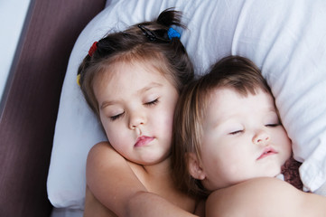 two little girls sleeping lying on bed. sibling sleep schedule in domestic lifestyle. cute sisters togetherness