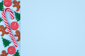 New Year composition with striped candy, pine tree, candle and gingerbread man. Christmas concept background. Flat lay, top view of festive still life