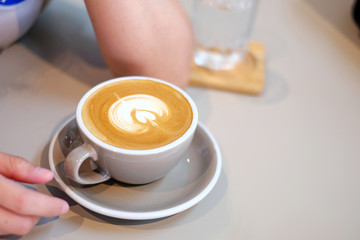 Hands of young woman in cafe. Cup of latte coffee closeup.