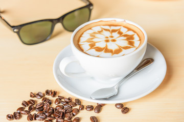 hot cappuccino coffee with sunglasses on table