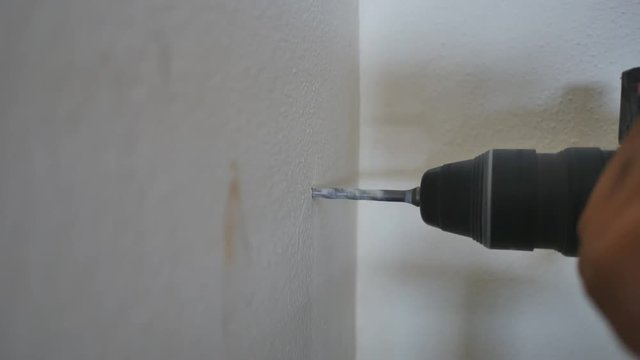 Hand close up of a man to drilling concrete and tighten screw for install water pipe in kitchen room