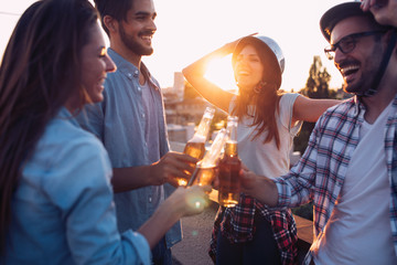 Young friends hanging out with drinks on rooftop