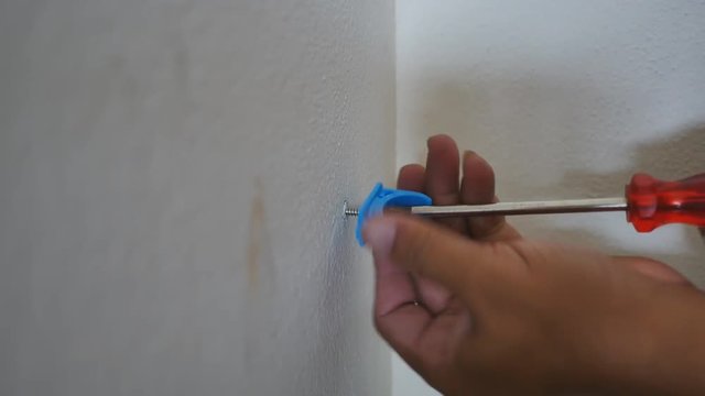 Hand close up of a man to drilling concrete and tighten screw for install water pipe in kitchen room