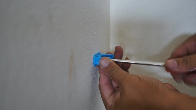 Hand close up of a man to drilling concrete and tighten screw for install water pipe in kitchen room