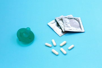 Baby nipple as symbol of pregnancy. Birth control pills and condom on blue background.