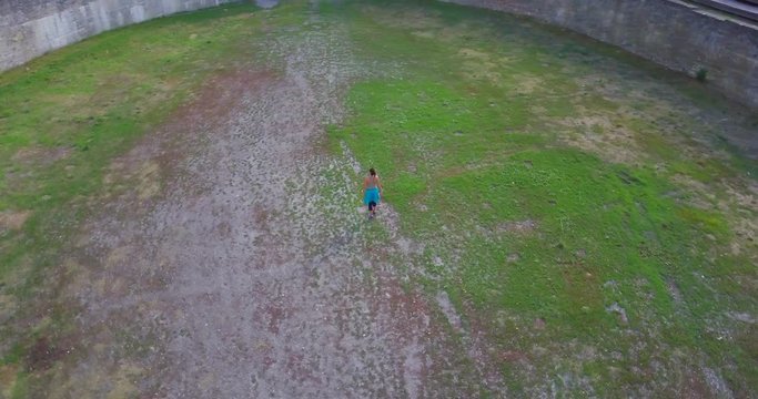 Sporty Girl Walking and Opening the Arms in The Roman Amphitheater of Martigny, Valais - Aerial Orbiting Shot
