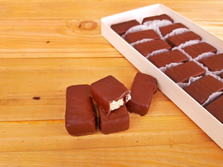 Assorted sweet chocolates in a box on wooden background