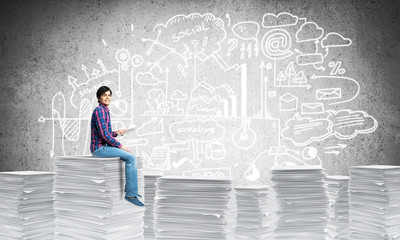 Attractive man sitting on pile of paper documents.