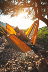 Traveler woman relaxes in a hammock on a rocky seashore