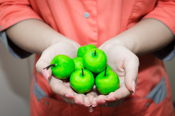 The young girl's hand holding a small green Apple. Nutritionist recommends apples.