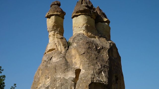 Close up low angle tilt up of a cone-shaped rock formation with erect column-like structures on top