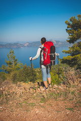 Traveler woman with backpack stands on the cliff