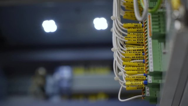 Inside of electrical control panel, cable terminal socket and electrical control device with yellow cable pins. Switchboard with pins and connectors inside.