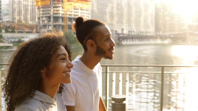 Cute African American couple walking together along the Chicago River after their morning workout.