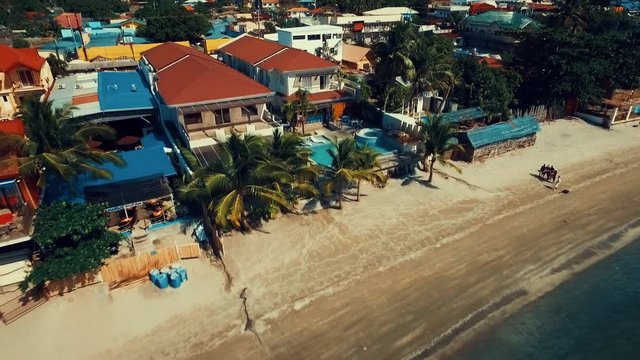 Drone shot flying backwards overviewing the beach and city of Subic in the Philippines.