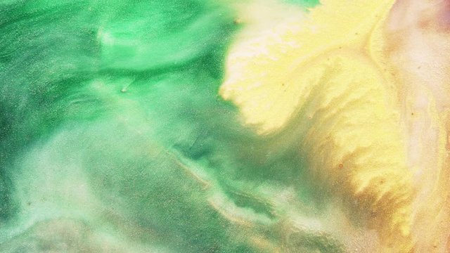 Colorful sparkling paints mix in beautiful patterns. Oil ink of green, yellow, brown and other colors spread on the surface and mix one into another creating amazing textures and design.